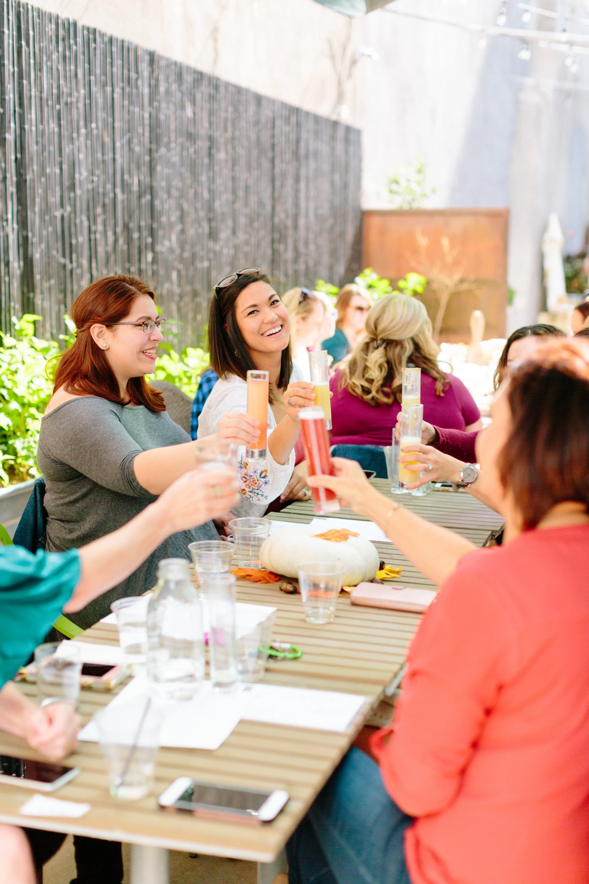 Guests toasting drinks around a long table on Nook’s patio