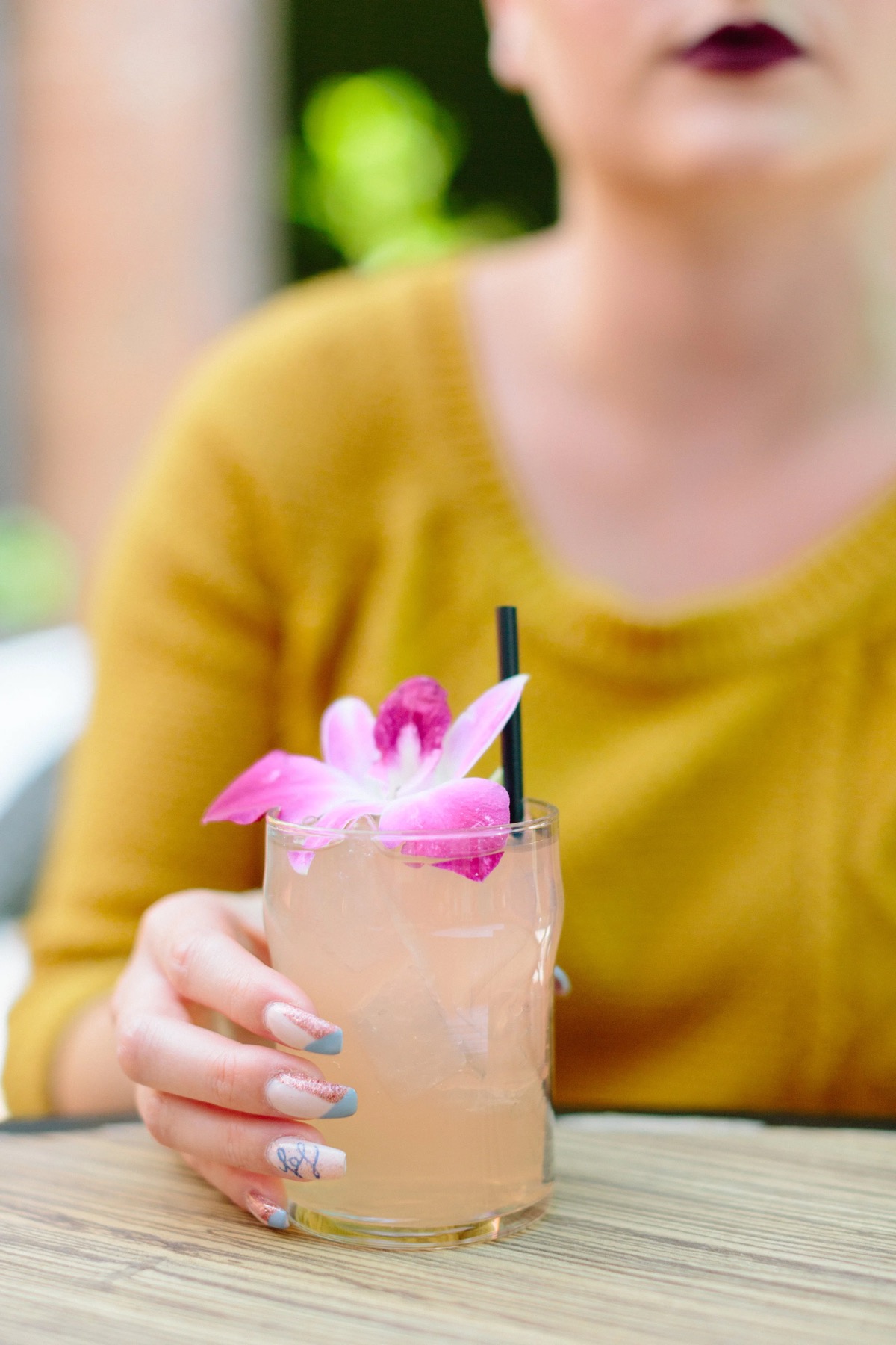 A guest holding a cocktail garnished with a pink orchid